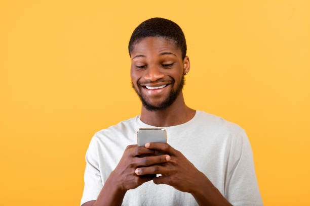 istock People and technology concept. Excited african american man using smartphone over yellow studio background 1322921005
