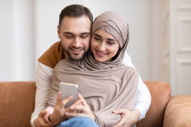 istock Happy Muslim Couple Using Mobile Phone Together At Home 1322921452