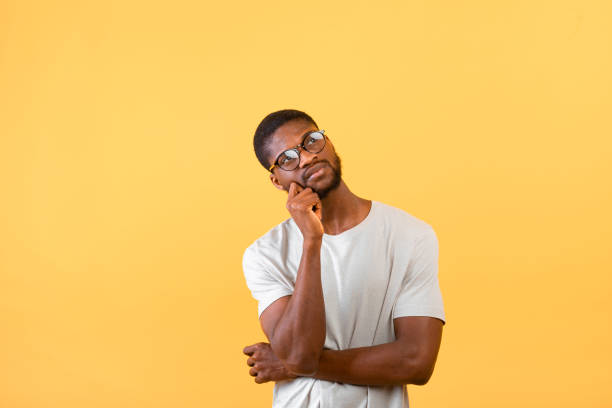 istock Searching for idea. Thoughtful african american guy looking up at free space, posing over yellow background 1322922158