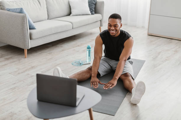 istock Happy African Man Doing Stretching Exercise At Laptop At Home 1322922438
