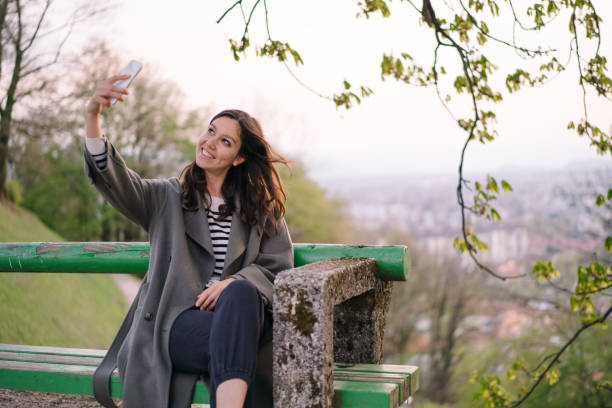 istock Young woman relaxes on park bench near downtown district 1322924571
