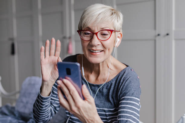 Senior woman is communicating on video call in bedroom stock photo