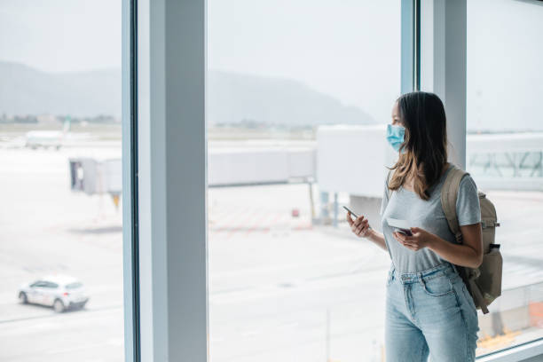 junge frau trägt gesichtsmaske geht durch flughafen - clothing anticipation central europe switzerland stock-fotos und bilder