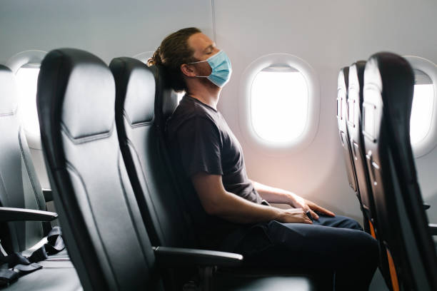 istock Young man wearing face mask relaxes in airplane 1322925664