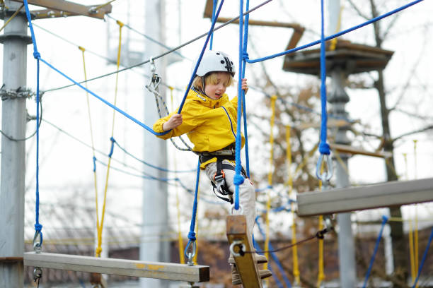 симпатичный мальчик весело провести время в приключенческом парке для детей amoung веревки, лестницы, мосты. испуганный ребенок преодолевает  - 12042 стоковые фото и изображения