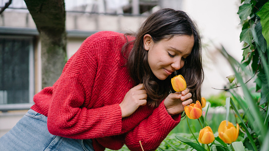 She bends down to smells surrounding flowers