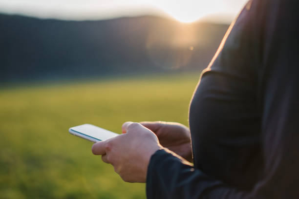 istock Female trail runner texts on cellphone in grassy meadow 1322927536