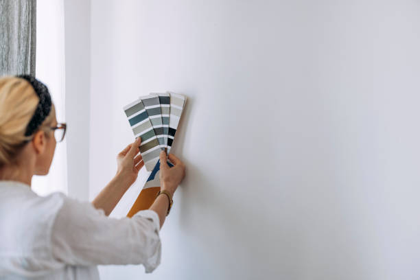 mujer joven sosteniendo carta de colores en la pared blanca - muestra de colores fotografías e imágenes de stock