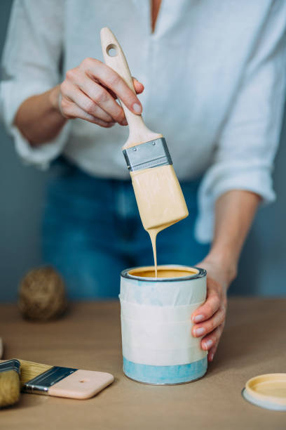 istock Woman Testing Yellow Paint With Paintbrush At The Table 1322927696