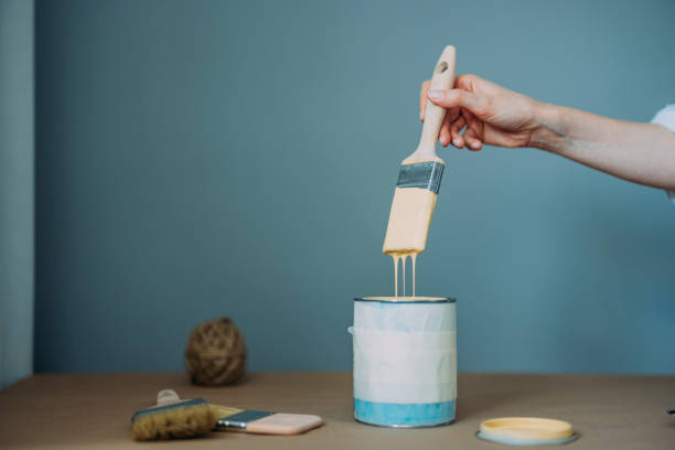 istock Woman Holding Paintbrush And Testing Yellow Paint 1322927718