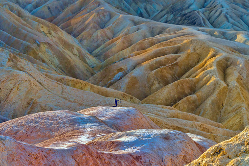 Sunrise embrace in the vastness of famous Zabriskie Point. The vast wilderness below the sky unfolds in silent admiration, creating a breathtaking canvas of nature's first light