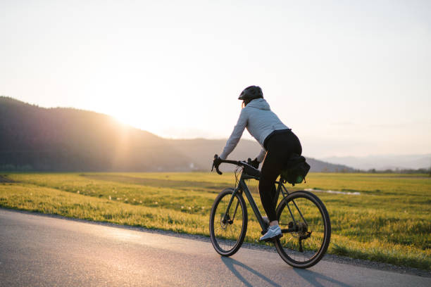 Young woman bikes down country road at sunrise stock photo