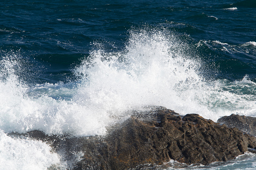 waves with white foam breaking over brown rocks on the coast of A Coruña in Spain