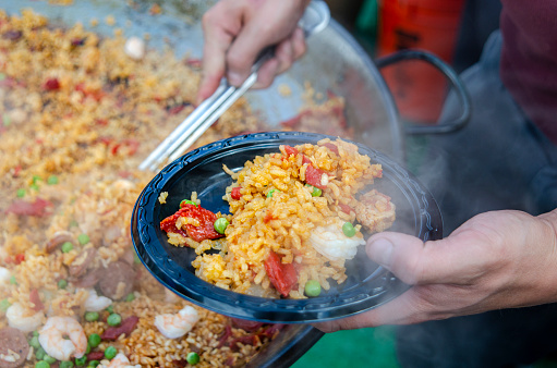 Vail, Colorado, USA - October 4, 2015: Residents and tourist are served Spanish Paella on a beautiful Fall afternoon at the The Vail Farmers Market in Vail on Meadow Drive. Entering its 17th year, the event started with a few tents and now has grown to over 135 tents for 17 Sundays of the summer. The market offers outdoor shopping and entertainment for everyone and brings people from all over to enjoy the Rocky Mountains on a Sunday. Visitors enjoyed strolling down East Meadow Drive in Vail while tasting treats and purchases arts and crafts from Colorado. The Market began on Father's Day June 17th and went through October 7th, 2015.