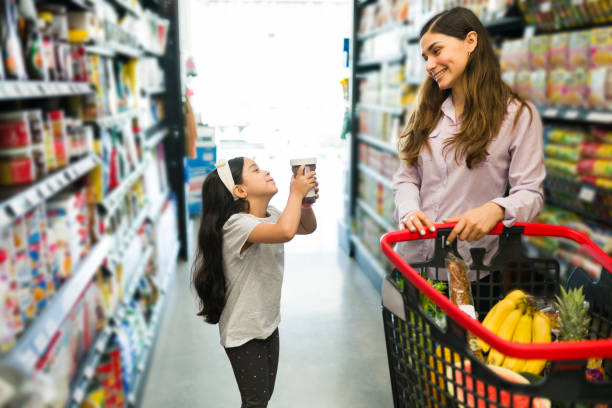 Can you purchase this delicious snack for me? Please, buy me chocolate. Adorable little girl asking her pretty mom to buy her hazelnut cream for breakfast at the supermarket pleading stock pictures, royalty-free photos & images