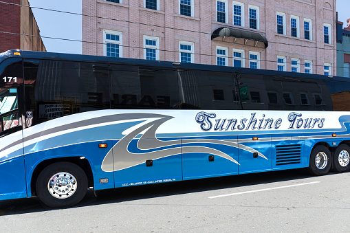 Mount Airy, NC, USA-5 June 2021: A shiny blue Sunshine Tours bus passes down Main Street.