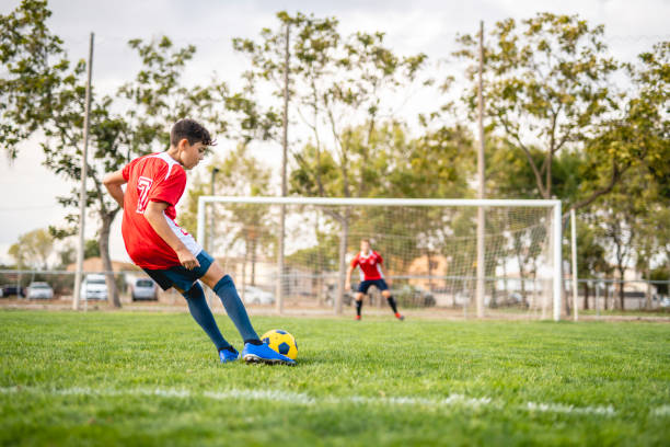 istock Athletic Boy Footballer Practicing Kick to Goal 1322942726
