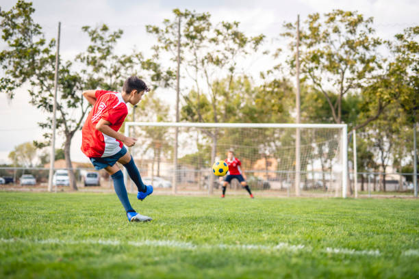 istock Athletic Boy Footballer Practicing Kick to Goal 1322942728
