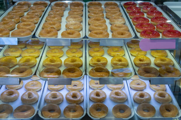 istock Trays full with delicious glazed donuts placed on a shelf inside a glass display cabinet. 1322944838