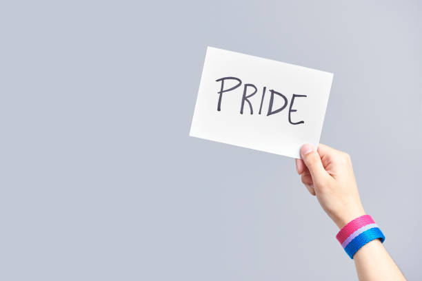 istock Hand with a bisexual flag bracelet holding a paper with a message: pride 1322947590