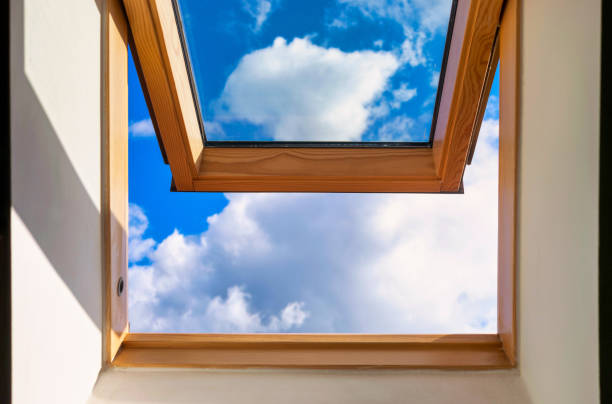 istock Looking up to the blue cloudy sky through modern square window 1322948328