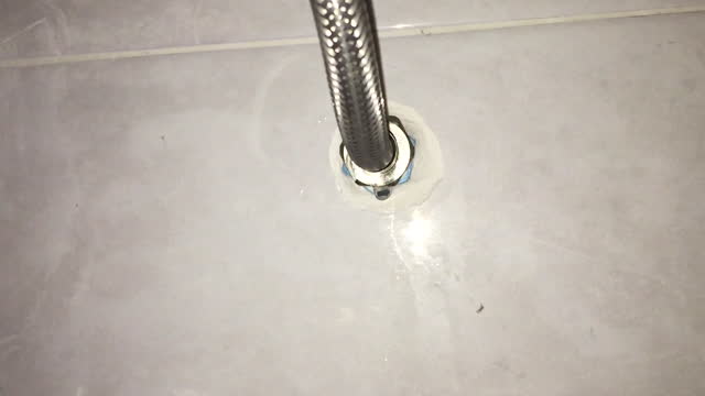 Damaged leaking water tap hose in the bathroom of house