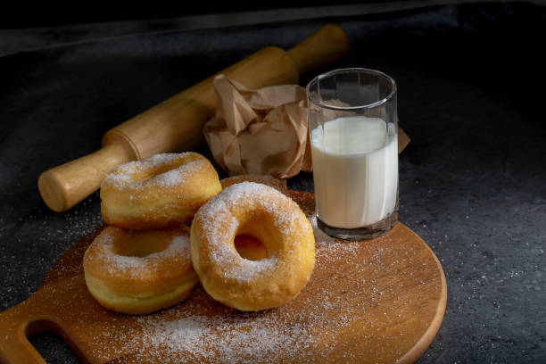 istock Donuts with sugar on a wooden plate over a dark table background. 1322959213