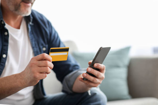istock Unrecognizable man using smartphone and holding credit card 1322963608