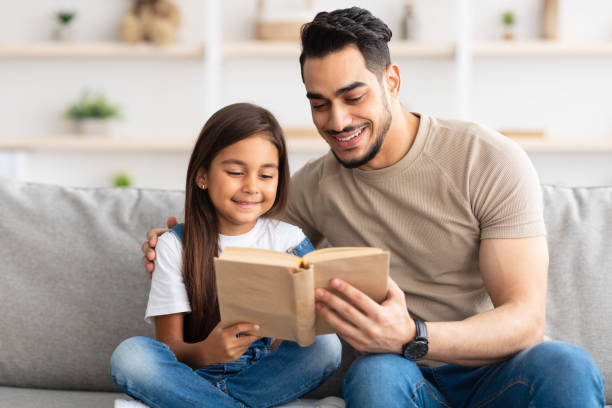 istock Dad and daughter reading book spending time together at home 1322963675