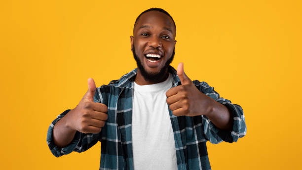 istock Excited Black Guy Showing Thumbs-Up With Both Hands, Yellow Background 1322963803