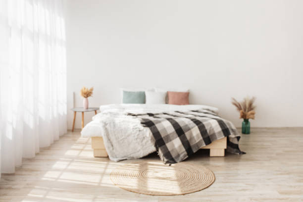 istock Contemporary boho design in minimalist. Bed with pillows and blanket, table with dry plants in vases 1322963827