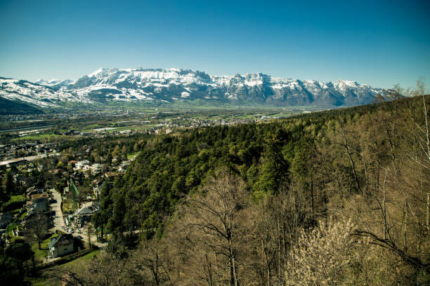 Aerial view of snow-covered rolling hills with a majestic mountain range in the background, showcasing the beauty of a winter landscape.