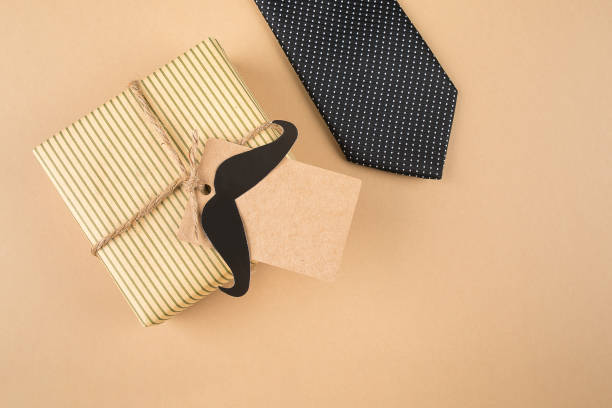 istock Gift box with tag, tie on neutral background. Top view, copy space, flat lay. Father's day concept 1322966451