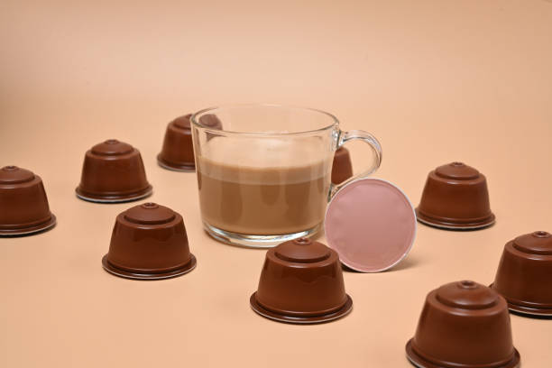 Coffee cup and coffee capsules on brown background.