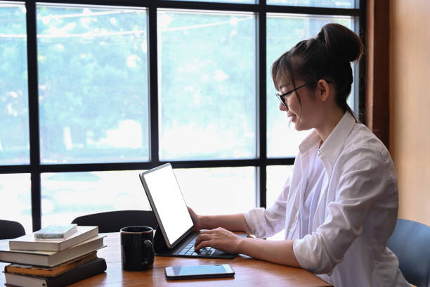 istock Side view of female student sitting in library and using laptop computer. 1322969252