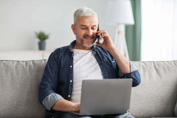 istock Cheerful senior man talking on phone and using laptop 1322973165