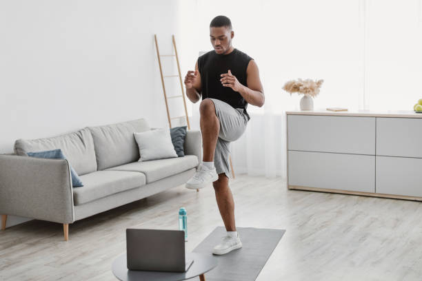 istock Black Man Doing Standing Knee Raise Exercise At Laptop Indoor 1322973212