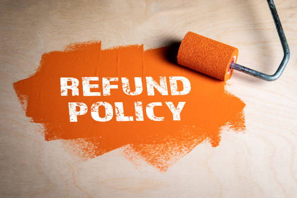 istock Refund Policy concept. Paint roller with orange paint on a wooden surface 1322973360