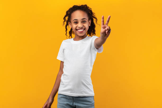 ritratto di ragazza nera sorridente che mostra il segno di pace - child celebration cheering victory foto e immagini stock