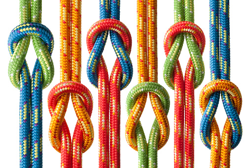 Knots with four ropes of different colors isolated on white background. The ropes are red, blue, yellow and green in color.