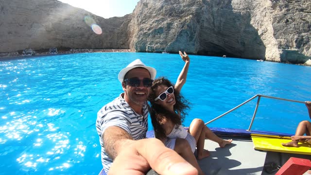 4K Video Vlogger Couple in love taking selfie and enjoying summer vacations on a boat in Zakynthos Greece - Navagio beach