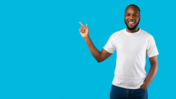 istock Black Man Pointing Finger Aside Smiling To Camera, Blue Background 1322975860