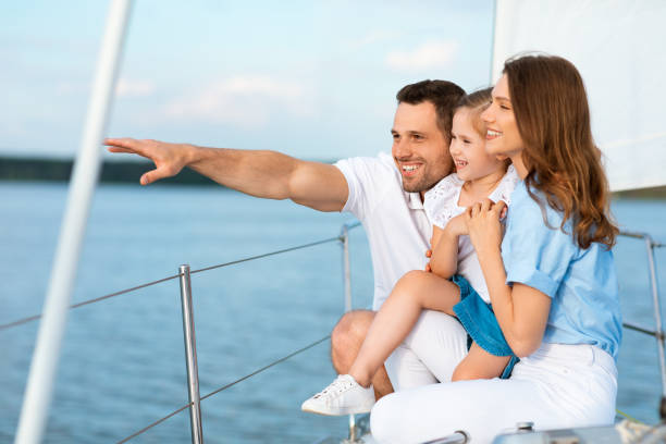istock Parents And Daughter Hugging Standing On Boat Deck Looking Aside 1322975888