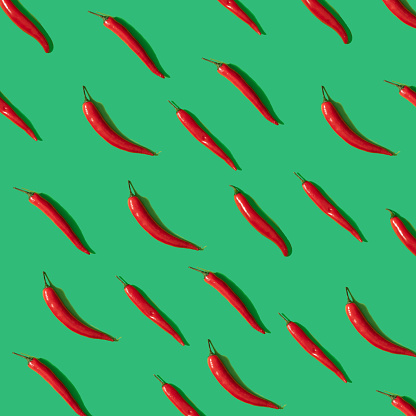 Red chili peperrs on green pastel background, flat lay pattern square composition