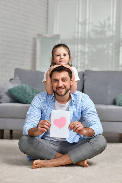 istock daughter congratulates her father and gives him postcard. 1322977905