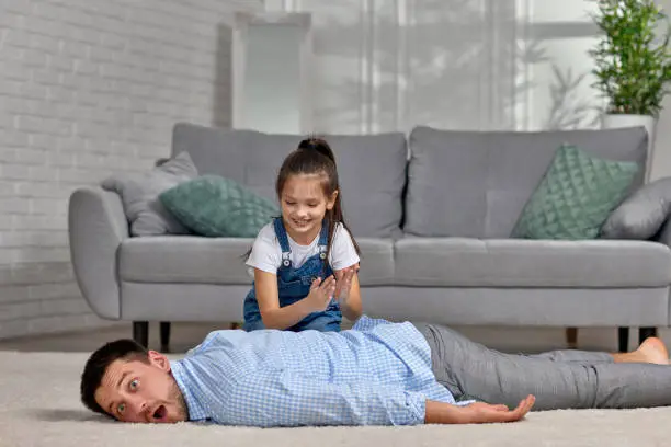 Photo of happy little child daughter doing massage to father