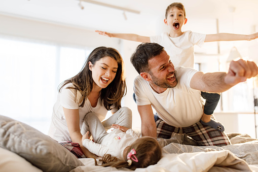 Cheerful family having fun during morning in the bedroom.