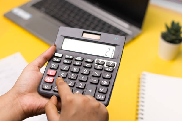istock Closeup of using calculator on yellow background stock image. 1322982518