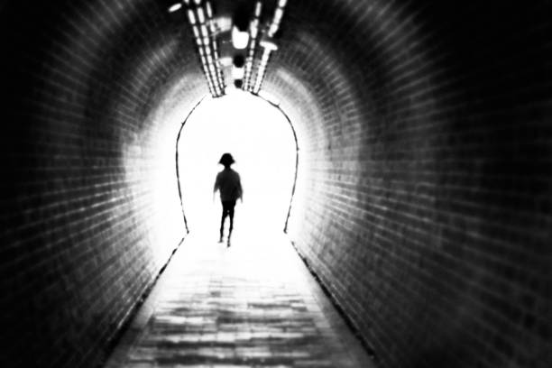 istock Girl walking through a tunnel towards light 1322983688