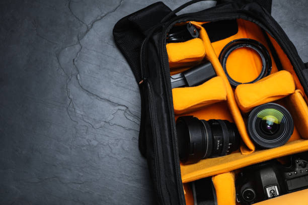 Professional photography equipment in backpack on slate table, top view. Space for text
